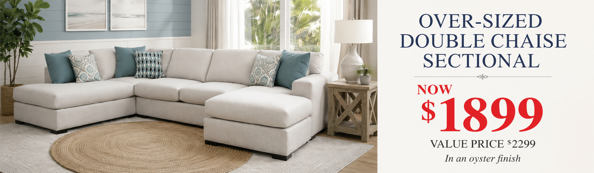 An over-sized double chaise sectional sofa in an oyster finish, styled in a bright living room with blue and white accent pillows, a round jute rug, and a wooden side table. The right side of the image features a promotional text overlay reading 'OVER-SIZED DOUBLE CHAISE SECTIONAL NOW $1899 VALUE PRICE $2299 In an oyster finish'.